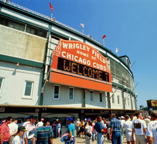 Large orange sign that reads "Wrigley Field, Home of Chicago Cubs"